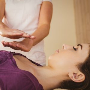 Young woman having a reiki treatment in therapy room